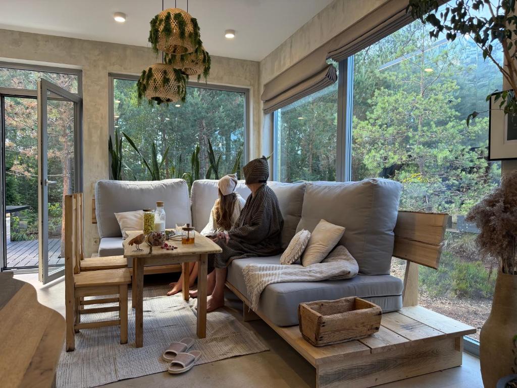 a man and woman sitting on a couch in a living room at Nest Spa Mirror Villas in Medemciems