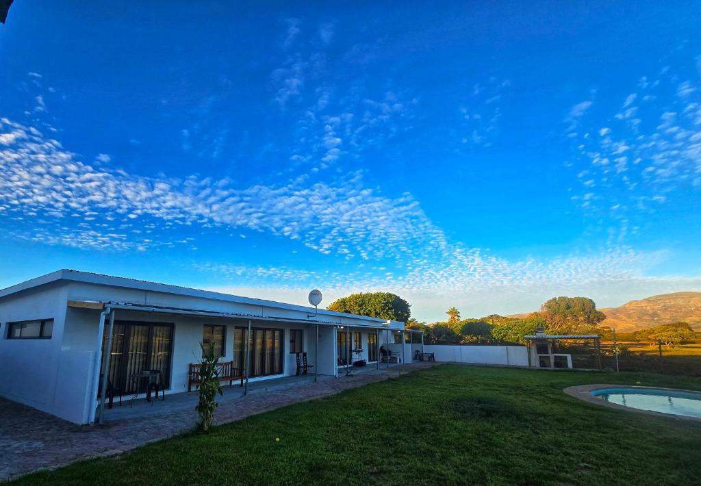 a white building with a grass yard and a blue sky at Princess Vlei Lodge in Grassy Park