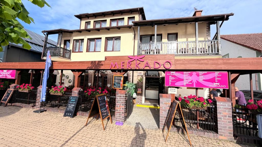 a restaurant with signs in front of a building at MERKADO in Darlowko