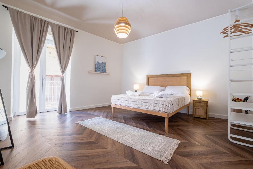 a white bedroom with a bed and a wooden floor at BISCOTTAI Port Apartments in Trapani