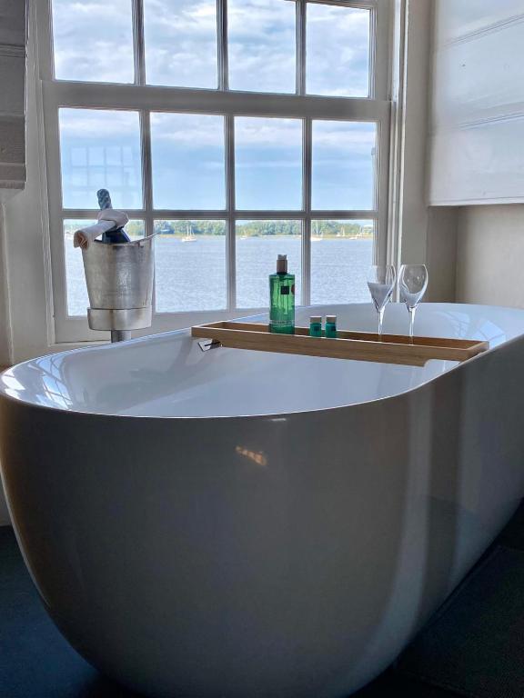 a bath tub with two wine glasses and a window at de Campveerse Toren in Veere
