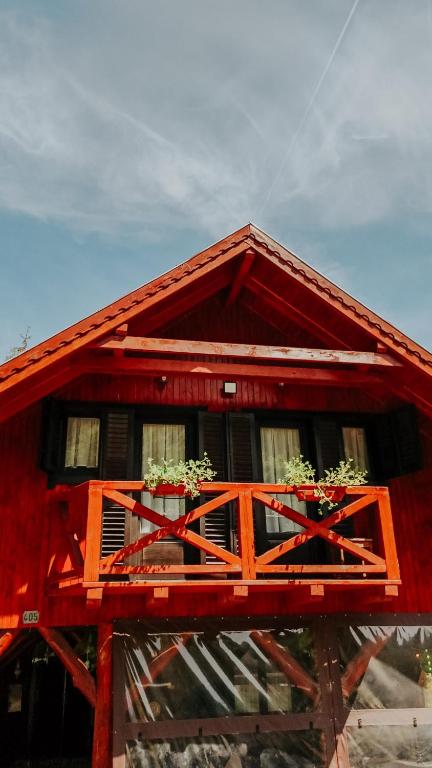 a red house with two windows and flowers on it at Hanul Morii in Ciucea