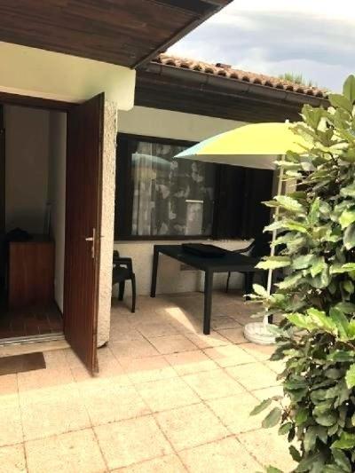 a patio with a table and an umbrella at Location appartement plain pied T3 à 8 KMS de l'océan in Lit-et-Mixe