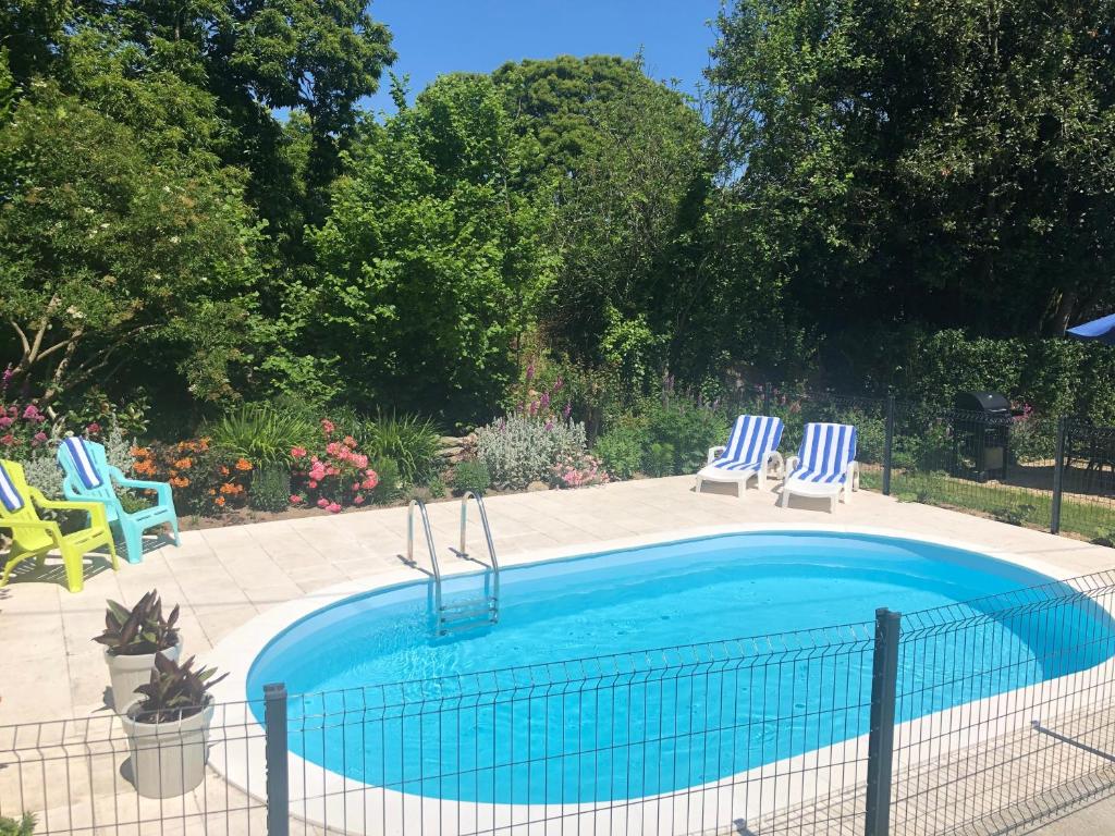 a swimming pool with two blue and white chairs at Walnut Tree Gîte in Boderel