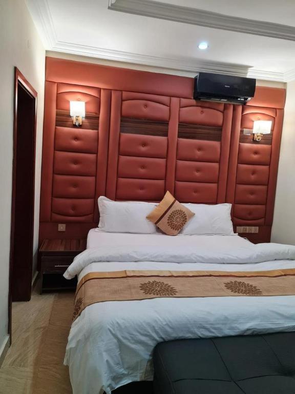 a bedroom with a large bed with a red headboard at Grand East Hotel in Akwa