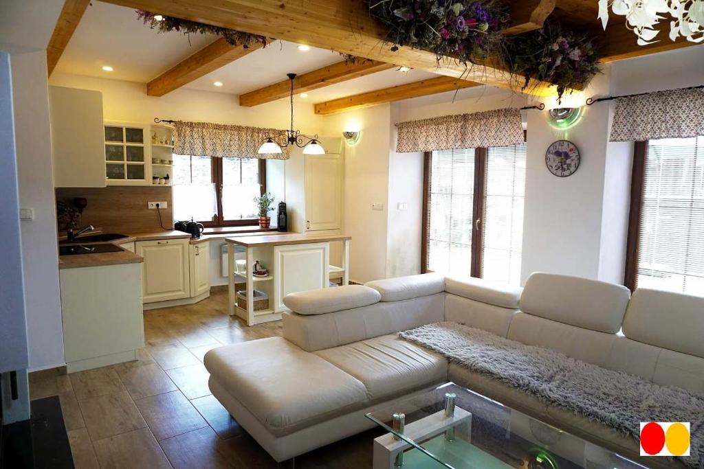a living room with a white couch and a kitchen at Rovenská Chalupa in Strážov
