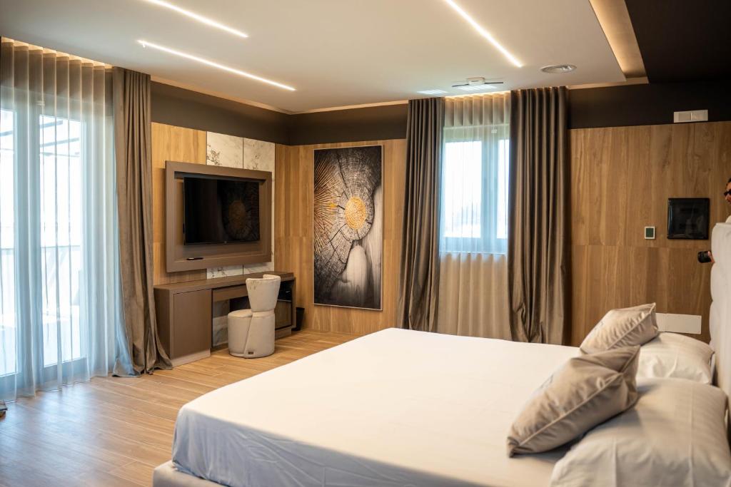 a bedroom with a white bed and a television at Tre Fontane Country House in Sperlonga