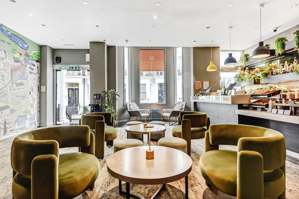 a restaurant with tables and chairs and a counter at Heeton Concept Hotel - Kensington London in London