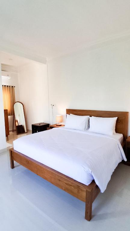 a bedroom with a large bed with white sheets and pillows at Rumah Merta Sari in Bingin Beach