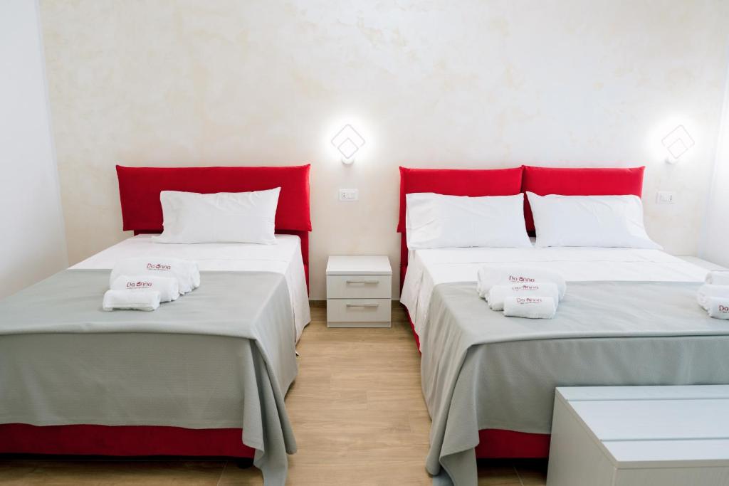 two beds in a room with red pillows at B&B Da Anna in Torretta