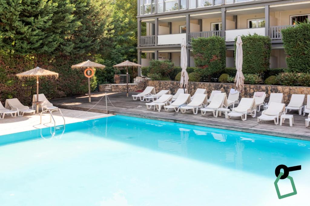 a pool at a hotel with chairs and umbrellas at Hotiday Corfu Kanoni in Corfu