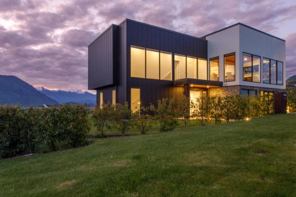 a house on a hill with mountains in the background at Grand Peninsula Lodge in Wanaka
