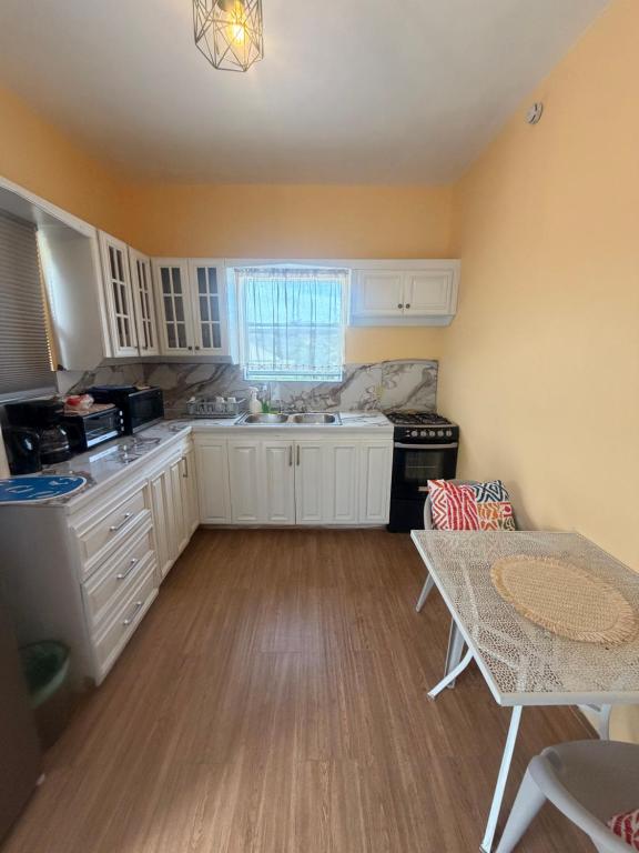 a kitchen with white cabinets and a table in it at Sunfusion apartment & Cottages in Saint Mary