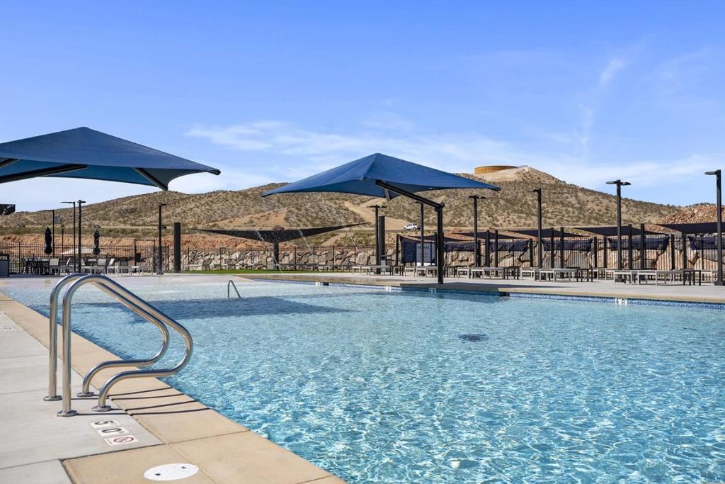 a swimming pool with blue umbrellas and tables and chairs at Desert View in Long Valleu in Washington