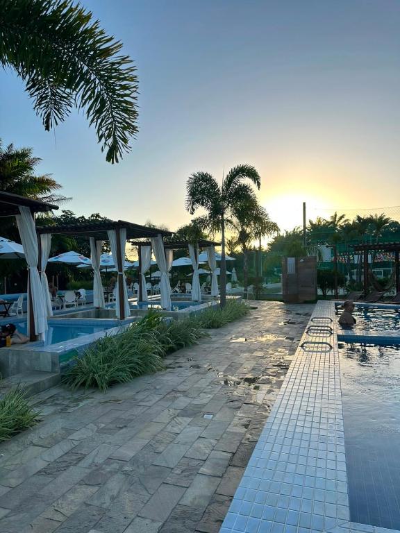 a pool at a resort with palm trees and umbrellas at Apartamento completo, moderno e bem localizado in Parnamirim