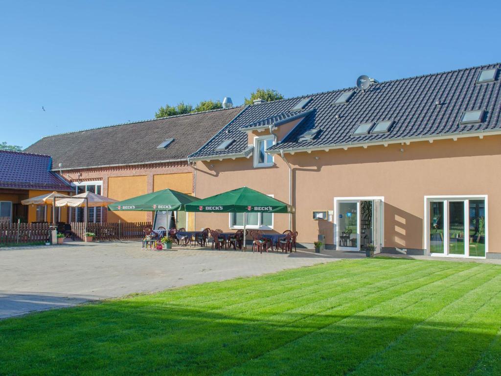 ein Gebäude mit einer Terrasse mit Tischen und grünen Sonnenschirmen in der Unterkunft Die Kulturscheune in Schilde in Schilde