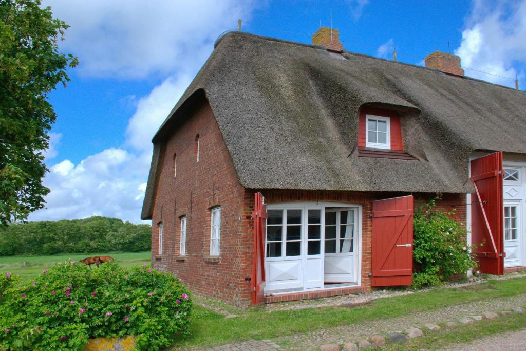 a small red brick house with a thatched roof at Van Gunst Hüs, Alkersum in Alkersum