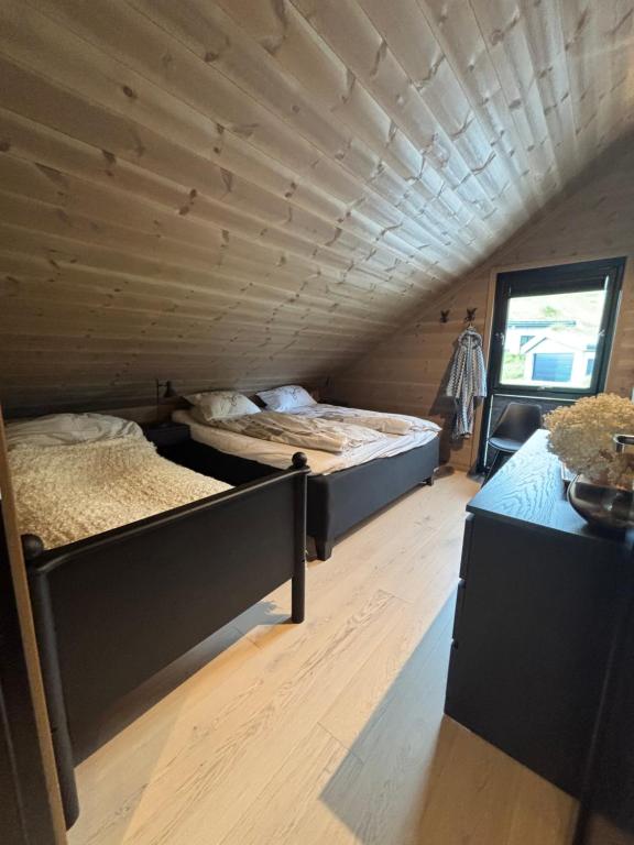 two beds in a room with a wooden ceiling at Rom med eget bad til leie felles inngang Uten kjøkken og stue Kun overnatting in Tjørhom