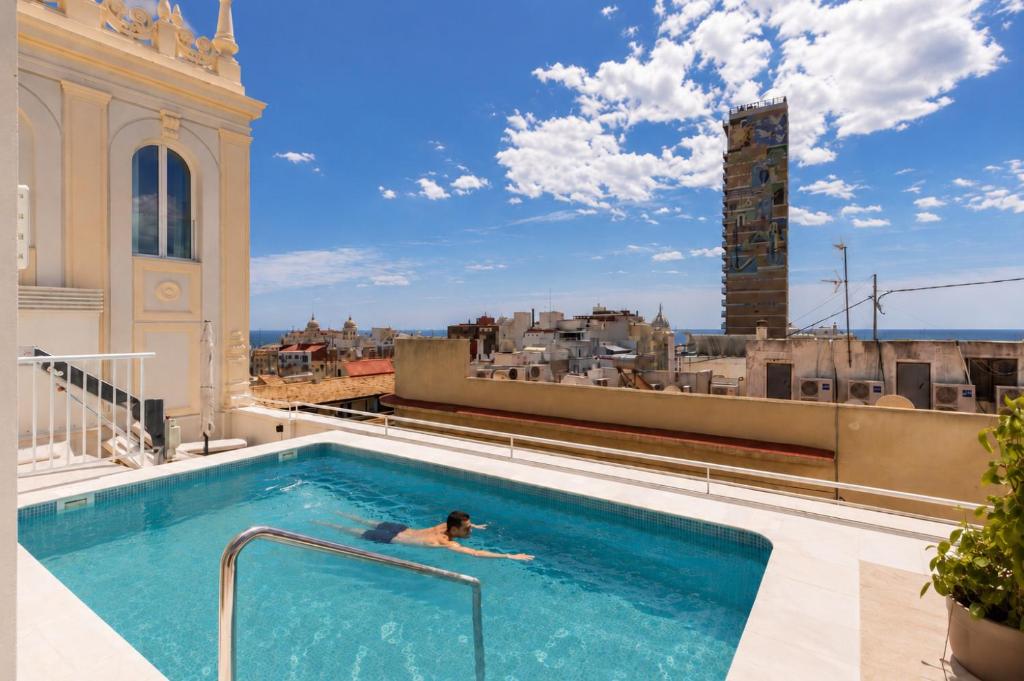 a person swimming in a swimming pool on top of a building at Líbere Alicante Rambla in Alicante