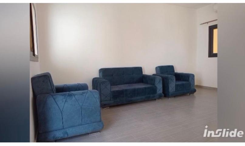 two blue chairs and a couch in a room at Perles de ngaparou in Saly Portudal
