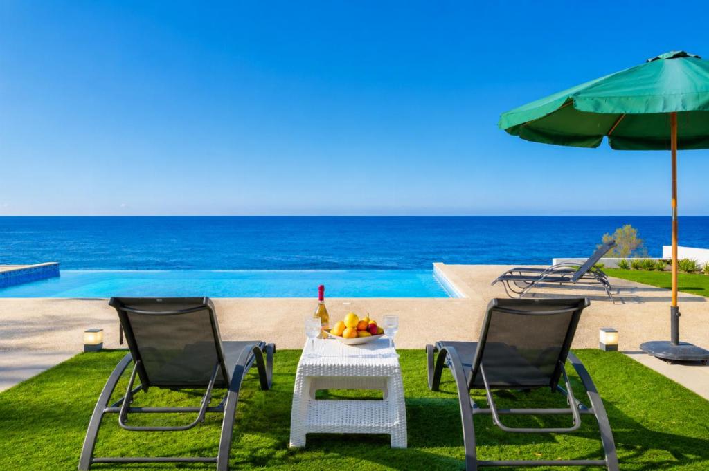 a table and two chairs and an umbrella and the ocean at Villa Stella Sunset in Nea Dimmata