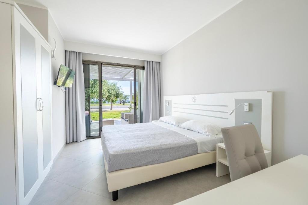 a white bedroom with a bed and a chair at Hotel Baia Di Trainiti in Vibo Valentia