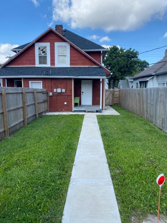 a red house with a fence and a sidewalk at The Heart house in Indianapolis