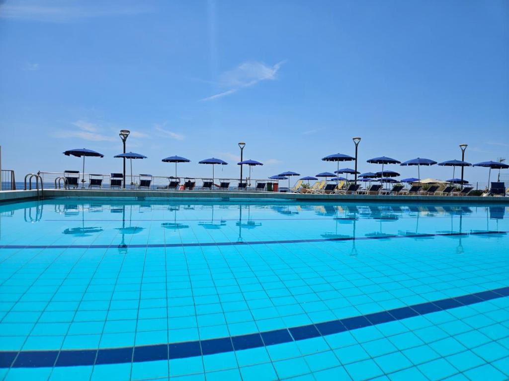 a swimming pool with umbrellas and tables and chairs at Casa Caribe - Piscina, Spiaggia e Parcheggio inclusi! GRATIS in Sanremo