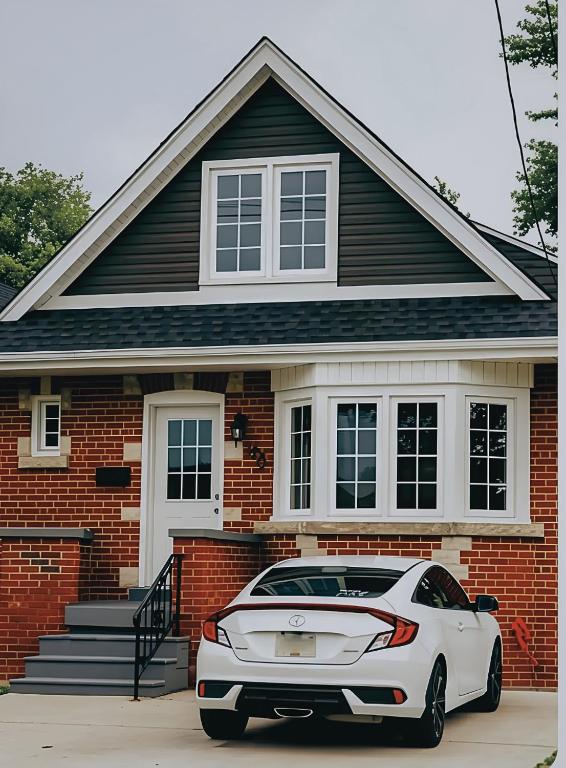 a white car parked in front of a brick house at Hamilton Central 3BR Family House in Hamilton