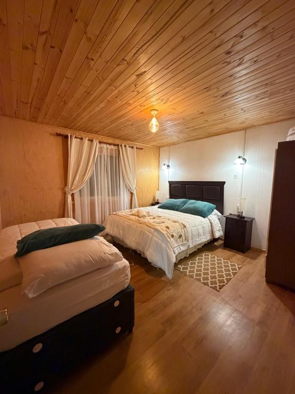a bedroom with two beds and a wooden ceiling at Cabaña A & M in Chaitén