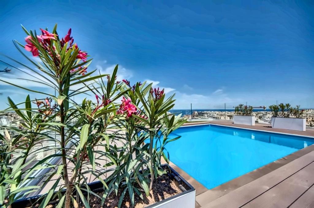 a view of a swimming pool with flowers on a balcony at Loft 23 Boutique Hotel in St. Julianʼs