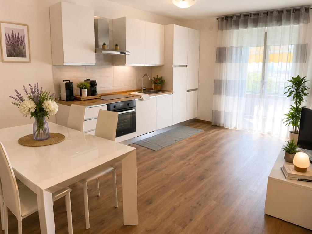 a kitchen with white cabinets and a table with chairs at Valtellinaresidence in Sondrio