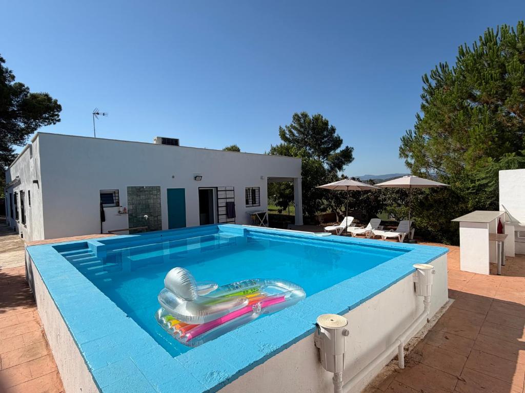 a swimming pool with a inflatable chair in front of a house at Tossal del Pla in Estivella