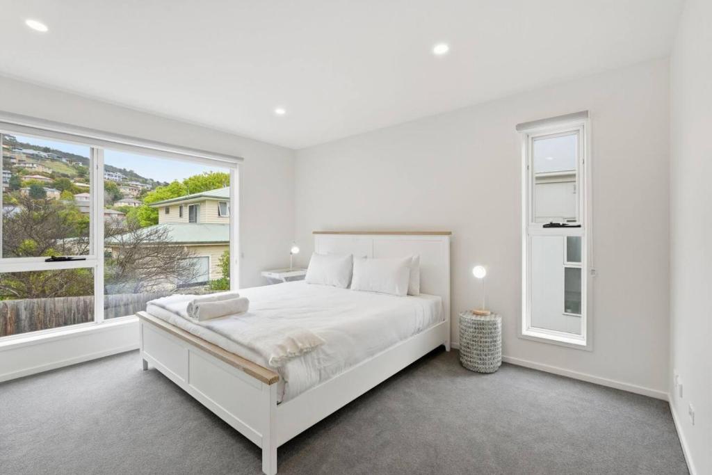 a white bedroom with a bed and a large window at Stylish Rosetta Waterview Stay in Rosetta