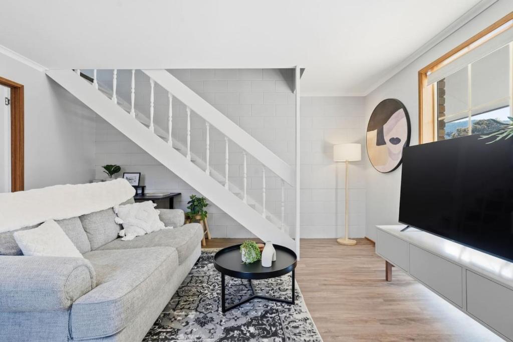 a living room with a couch and a tv at Cosy Unit Near MONA in Claremont