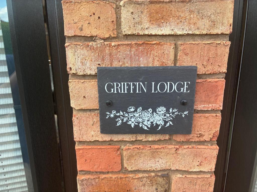 a sign on the side of a brick wall at Griffin Lodge in Warwick