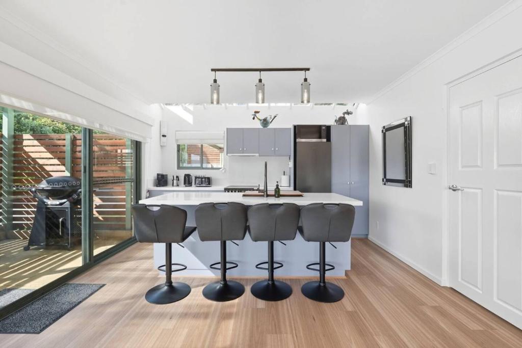 a kitchen with a kitchen island with four bar stools at Riverview Townhouse Retreat in Lindisfarne
