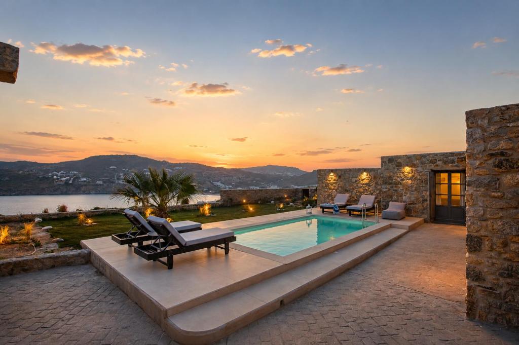 a villa with a swimming pool and a sunset at South Star private Mini Villa in Mikonos