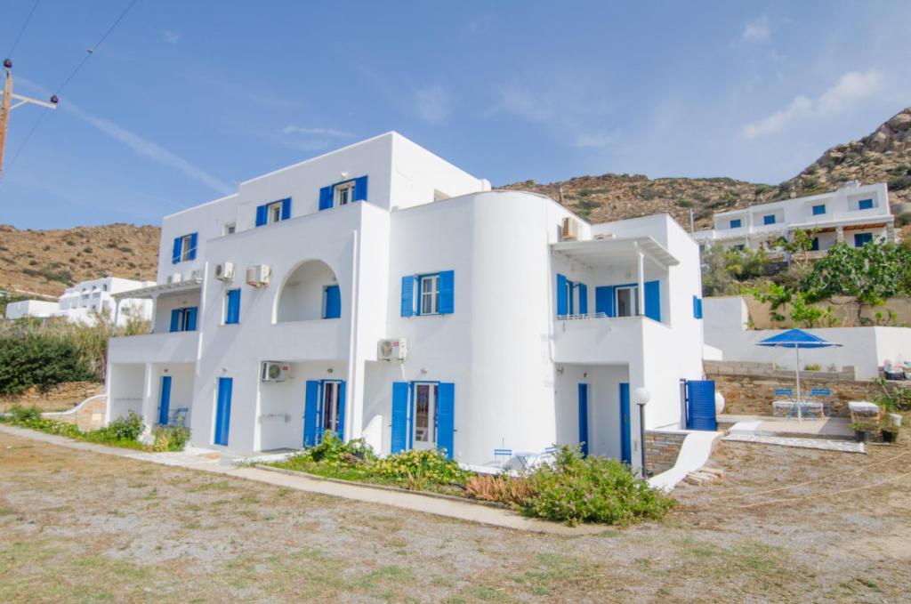ein großes weißes Gebäude mit blauen Fensterläden in der Unterkunft Sunshine Studios in Mylopotas