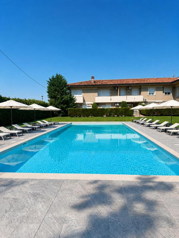 a large swimming pool with chairs and umbrellas at Hotel Venezia Park - ENJOY HOLIDAY in Colà di Lazise