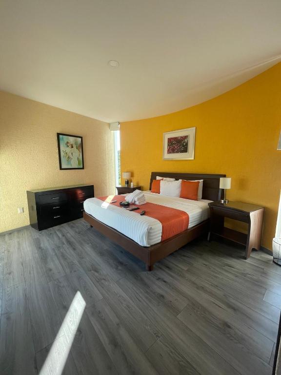a bedroom with a large bed and a yellow wall at Penthouse with Pool, Gym & A/C in Querétaro