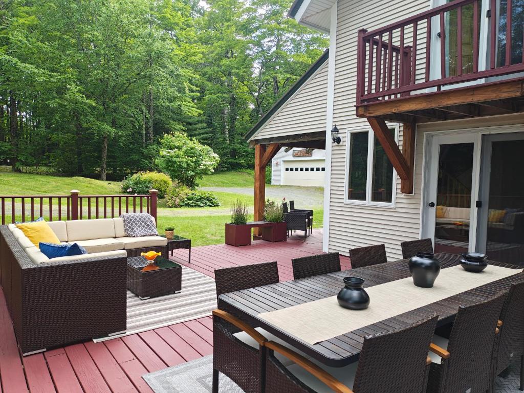 a patio with a couch and a table on a deck at Authentic VT Chalet, Hot tub, Fire pit, Mt Snow in Dover