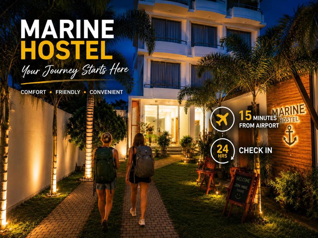 two people walking in front of a hotel at night at Marine Hostel at Negombo Beach in Negombo