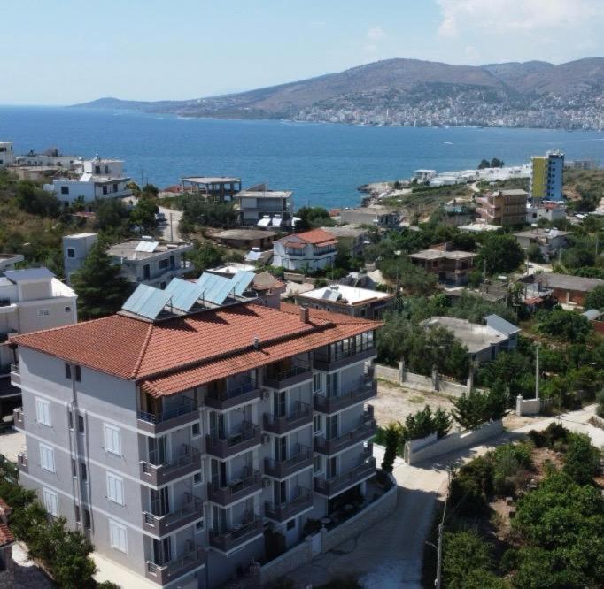 a building with a red roof next to the water at Golden Berden Boutique Apart-Hotel in Sarandë