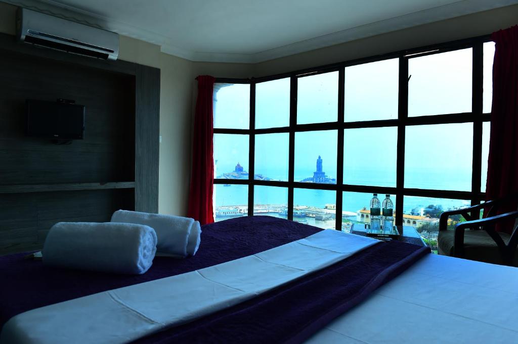 a bedroom with a large bed with a large window at HOTEL SEBAA PALACE in Kanyakumari