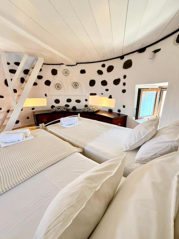 two beds in a room with a wall with rocks at Casa Milos Windmill Alonissos in Alonnisos