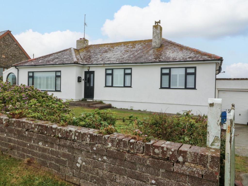 a white house with a brick wall at Faraway in Rhosneigr