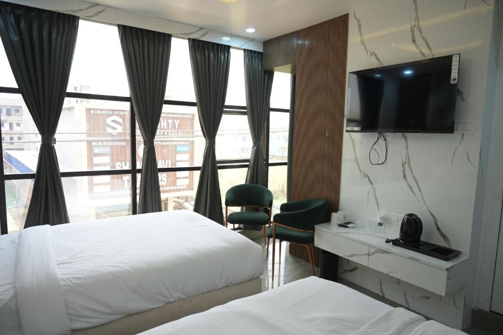 a hotel room with two beds and a flat screen tv at Hotel Surya Inn in Khagaul