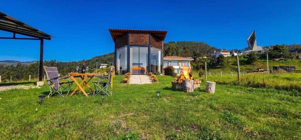 a small house with a fire in a field at Cabaña Pantano de Vargas con fogata y parrilla privado in Tibasosa