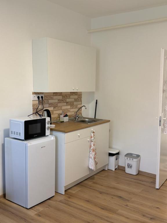 a small kitchen with a microwave and a refrigerator at Haromfa Apartman in Háromfa